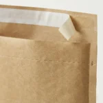 Close-up of kraft paper bubble mailer bag top closure showing self-seal pressure-sensitive adhesive strip and tear strip perforation line
