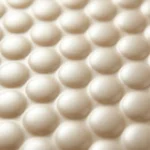 Close-up of pale pearlescent bubble mailer surface — large dome-shaped bubbles visible through matte satin champagne PE film, soft silky texture