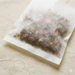 Close-up of glassine bag surface showing semi-translucent paper texture and heat-seal seam — 30gsm paper-only construction, no plastic film