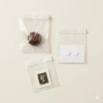 Glassine barrier paper bags containing chocolate, pharmaceutical tablets, and archival stamp — grease-proof, dust-blocking, acid-free paper bags with no wax coating or plastic film