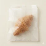 Close-up of glassine bag surface showing no grease bleed-through from oily food contents — supercalendered paper barrier without coating, wax, or plastic laminate