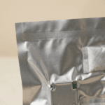 Close-up of heat-sealed top edge of aluminum foil vacuum bag showing hermetic seal and desiccant sachet